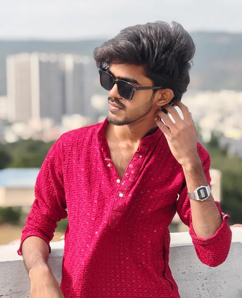 Abishek in a red kurta and sunglasses on a rooftop, the city behind him